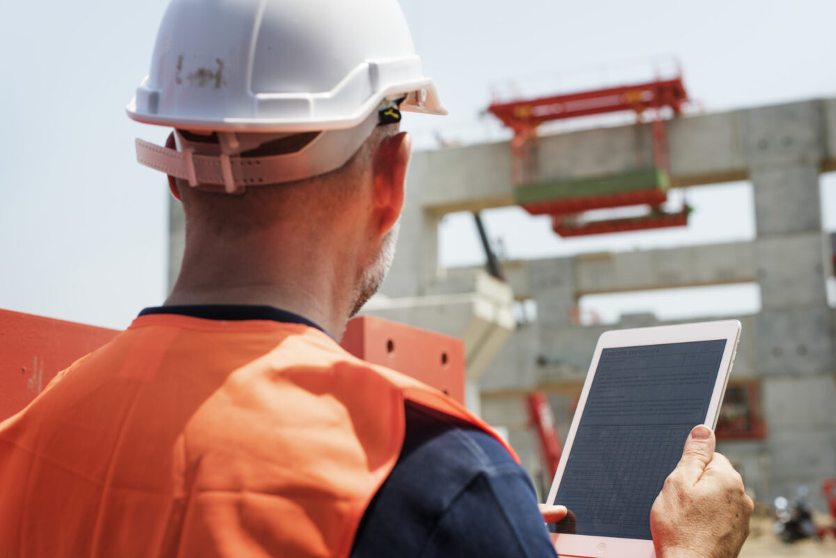 a man uses a tablet on the job site, showing the advantages of embracing technology in construction